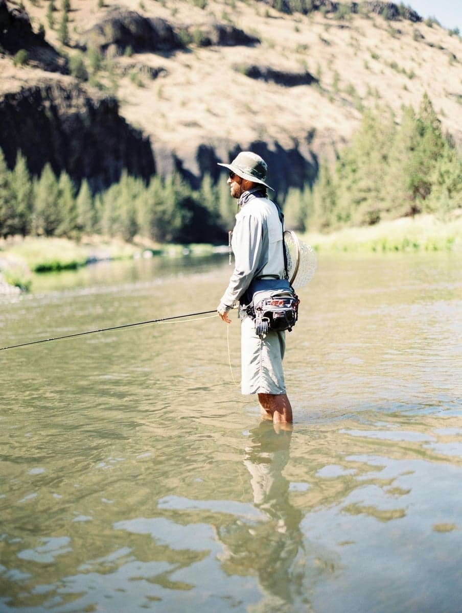 A fly fisherman wading the Deschutes River in Bend, Oregon on a sunny day