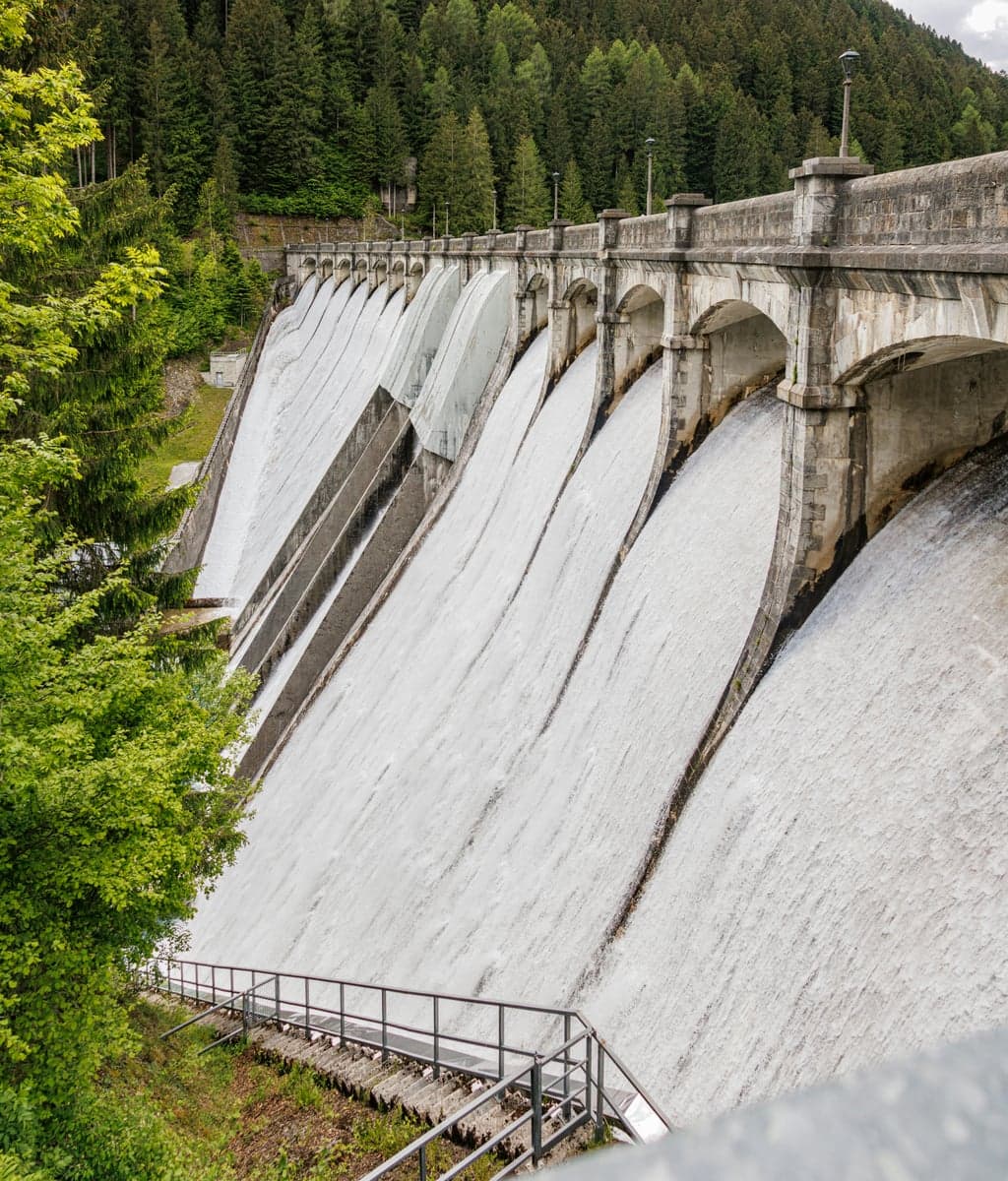 Water cascading over a dam spillway. Below this wall, the river runs cold and clear while every tributary upstream is blown out.
