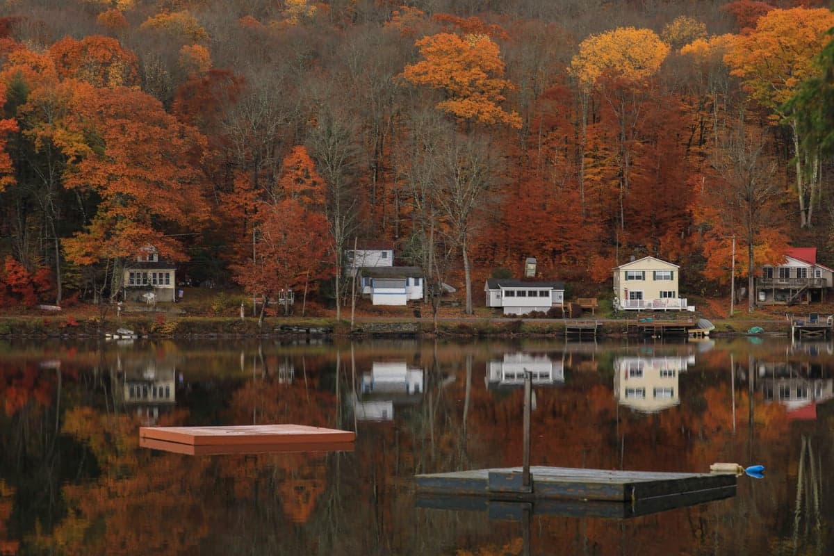 A Catskill village reflected in a lake during autumn. The towns along the Delaware offer lodging, dining, and a deep connection to fly fishing history.