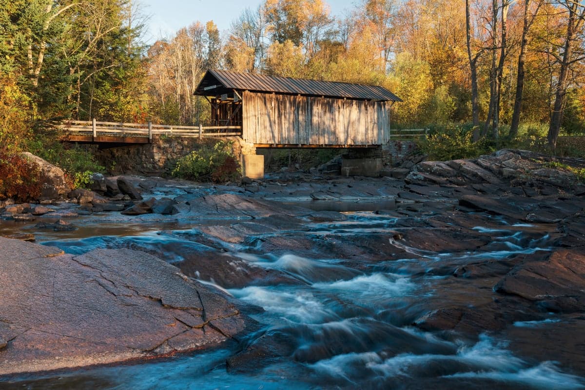 A covered bridge over a Catskills brook in autumn. The region's covered bridges and forested valleys define the landscape of the upper Delaware watershed.