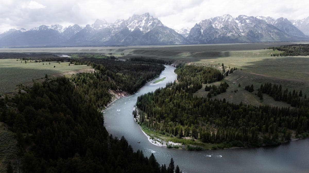 Snake River winding through lush valleys with the Grand Teton mountains shrouded in clouds