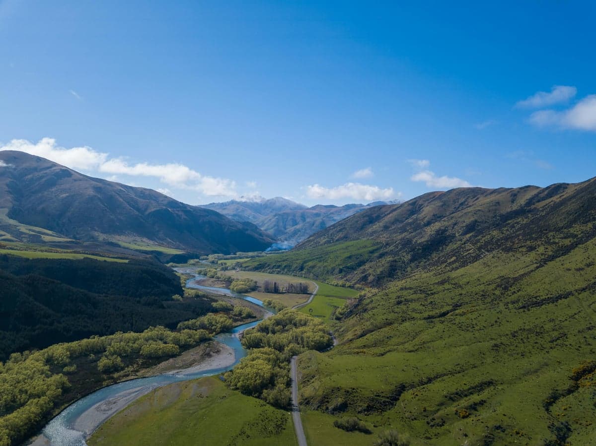 Aerial view of a river winding through a lush Appalachian mountain valley under a clear sky